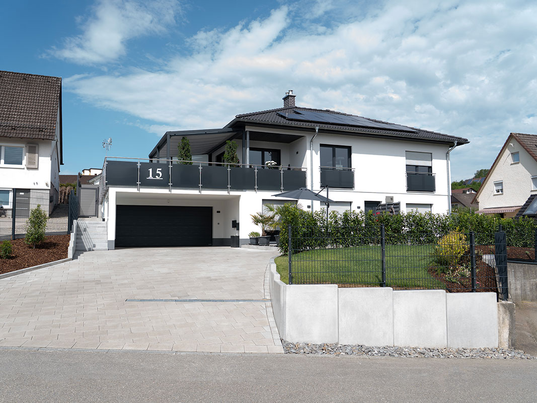 Haus der Familie Grimm mit gepflegter Hofeinfahrt und modernem Gartendesign.