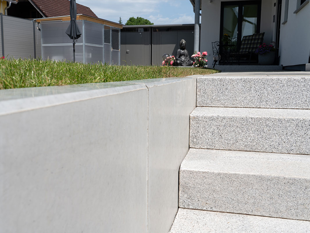 Betontreppe, die zur erhöhten Gartenfläche der Familie Grimm führt.