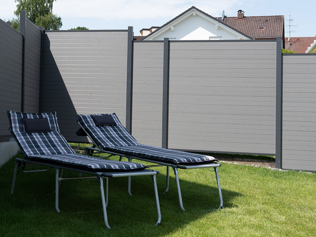 Garten der Familie Grimm mit zwei Liegen und moderner Sichtschutzmauer im Hintergrund