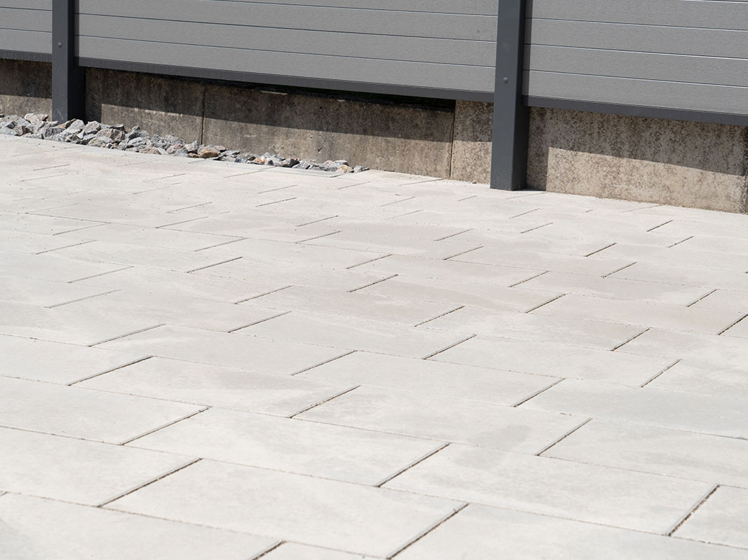 Pflastersteine auf der Terrasse mit angrenzendem Sichtschutzzaun in der Gartenanlage der Familie Grimm