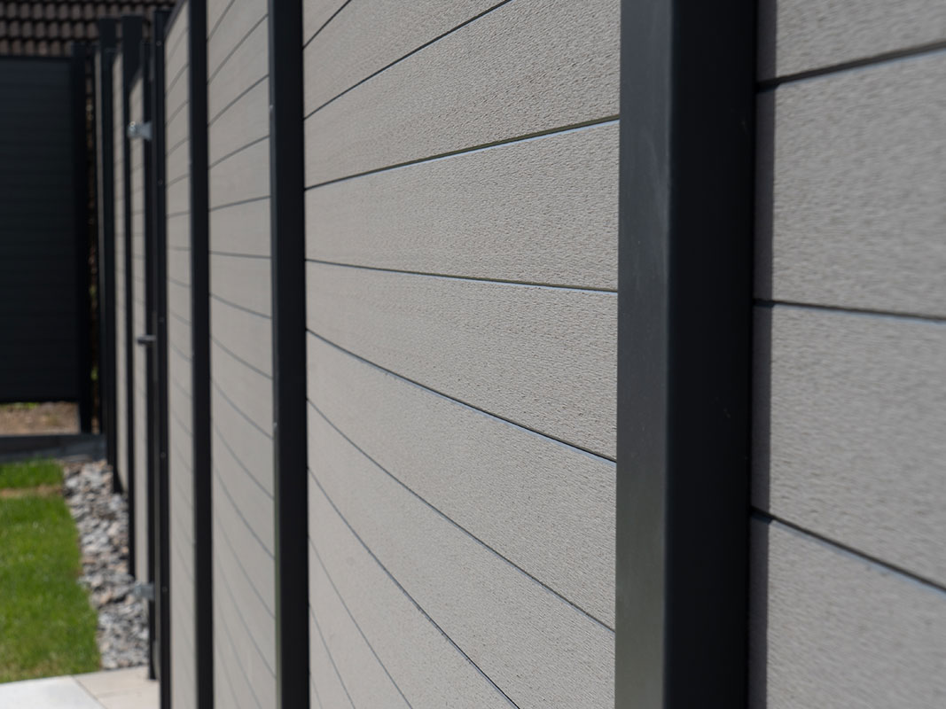 Nahaufnahme eines modernen WPC-Sichtschutzzauns in der Gartenanlage der Familie Grimm.