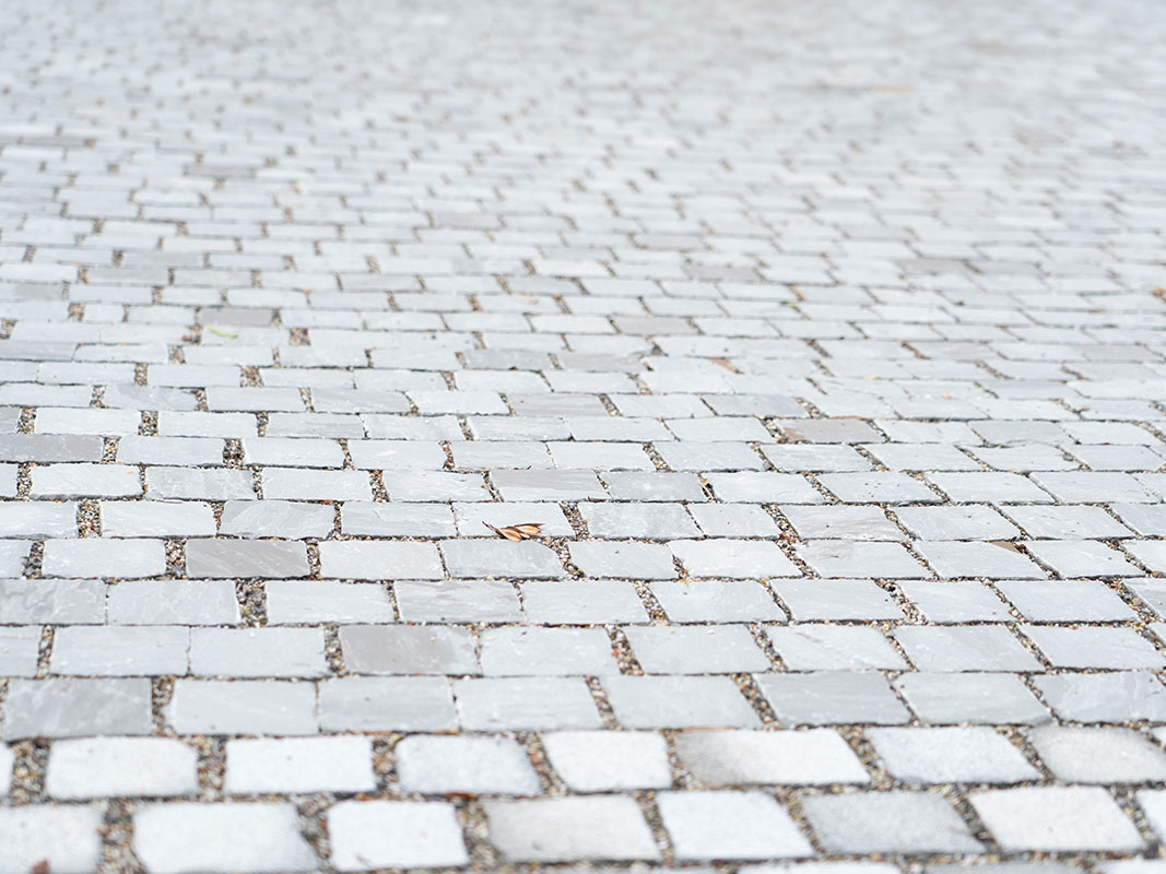 Nahaufnahme von Muschelkalk- und Sandsteinpflastersteinen in der Außenanlage der Nussbaum GmbH in Rottweil.