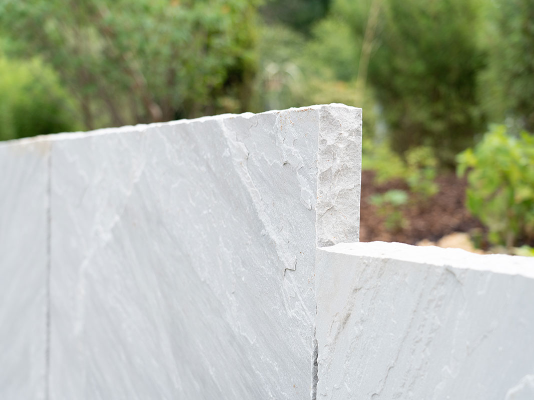 Nahaufnahme einer Natursteinmauer aus großen, nebeneinander stehenden Steinplatten, Teil der Außenanlage der Nussbaum GmbH in Rottweil.