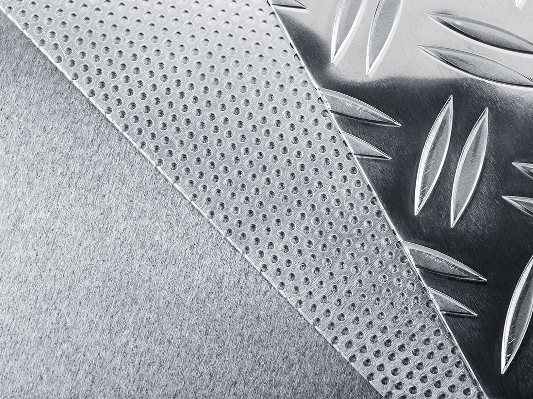 Drei verschiedene Sonderbleche in Großaufnahme: Riffelblech, Lochblech und glattes Blech, aufgefächert dargestellt.