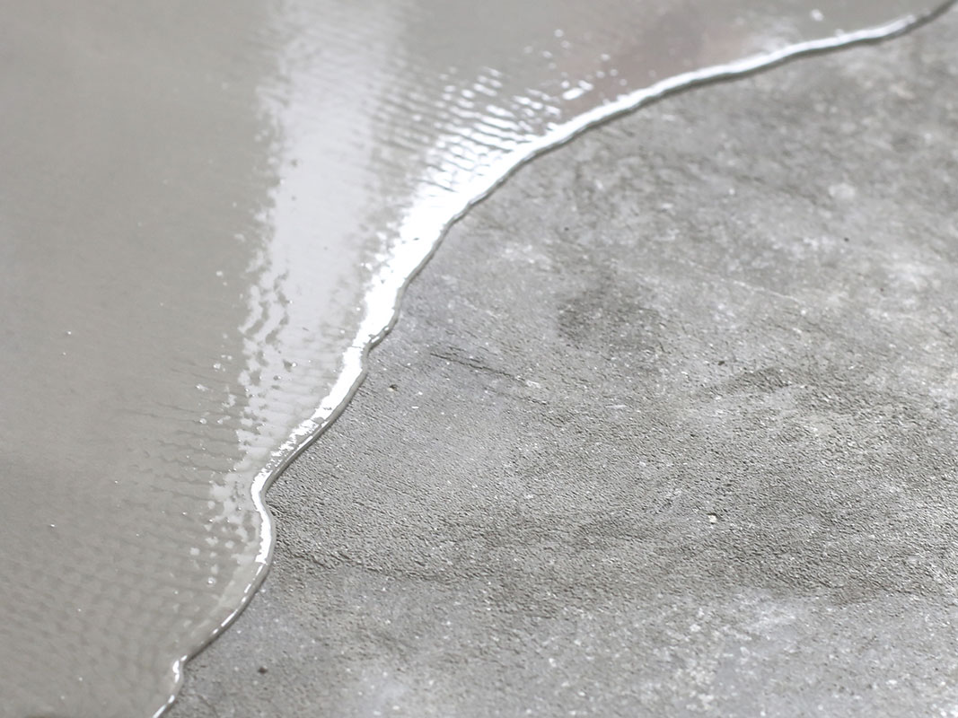 Flüssiger Beton fließt mit ausgehärtetem Beton zusammen, zwei Baustoffe für Hochbau und Rohbau im Vergleich.