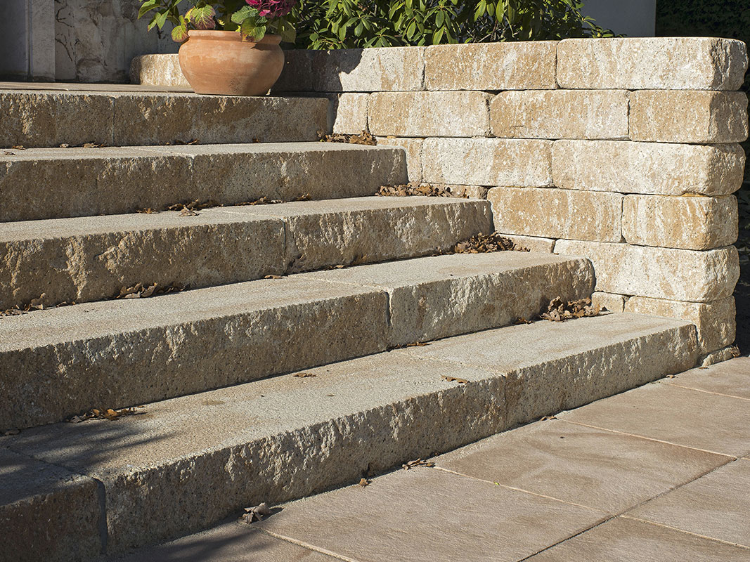 Nahaufnahme einer Treppe aus Natursteinpflaster mit robusten, gleichmäßig verlegten Steinen.