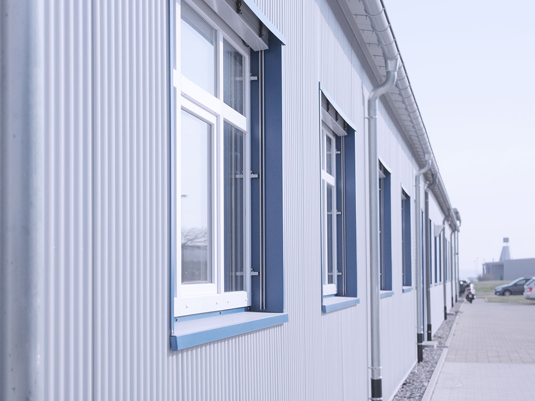 Fluchtansicht einer Außenwand mit modernen Fassadenblechen und Fenstern.