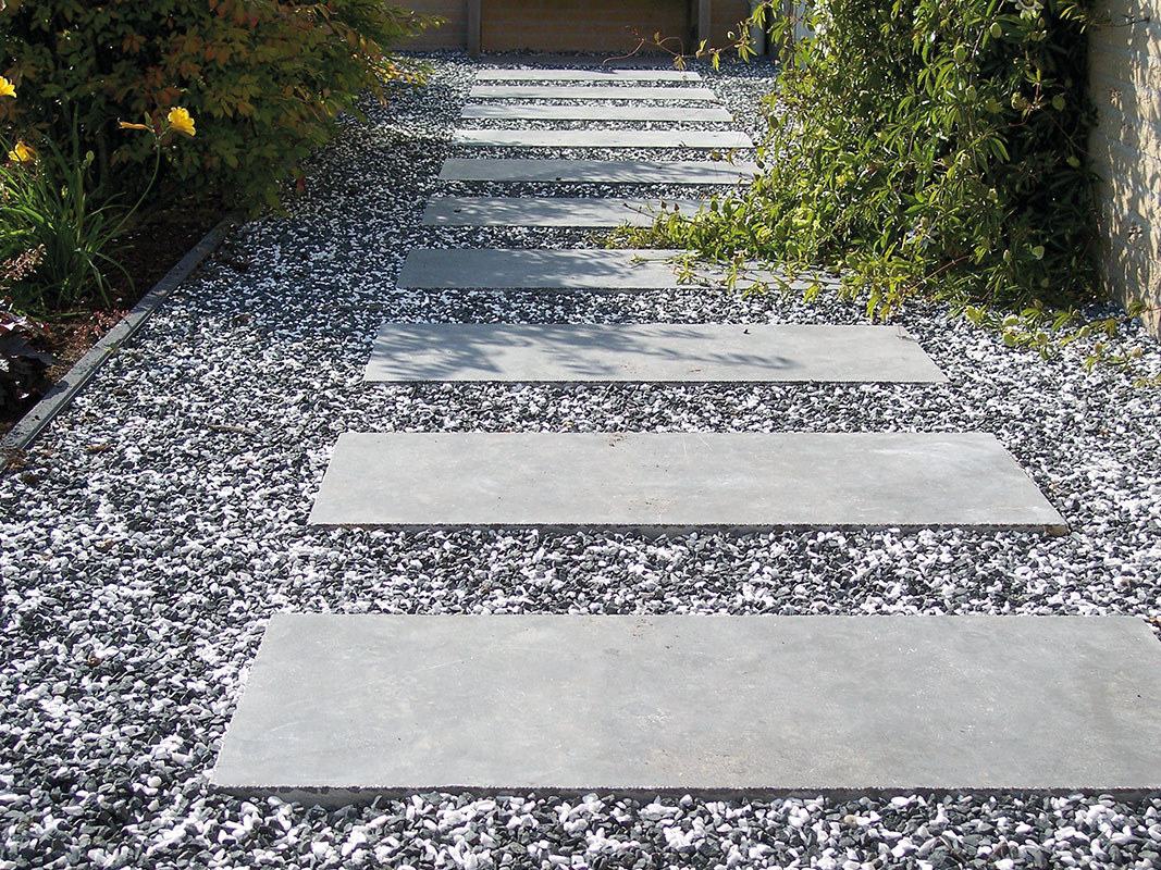 Gartenweg mit Zierkies und Edelsplitt, in der Mitte angeordnet große Steinplatten wie ein Zebrastreifen.