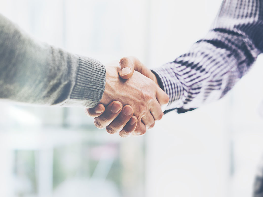 Zwei Geschäftspartner schütteln sich die Hand – Symbol für Vertrauen und Zusammenarbeit.