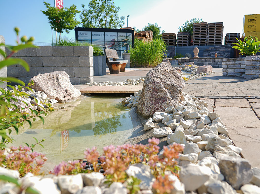 Steingartenausstellung in Niedereschach mit kleinem Bach, abgegrenzt durch verschiedene Steinarten.