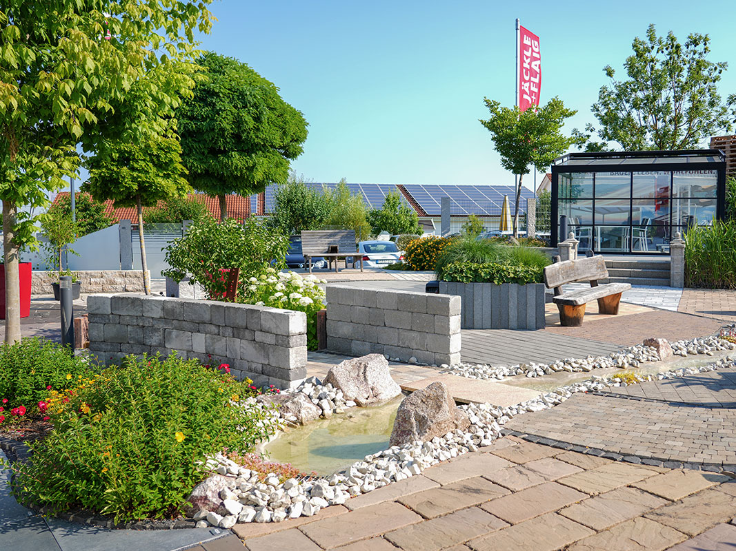 Steingartenausstellung in Niedereschach mit Pflastersteinen, kleinem Bachlauf, Holzbänken und Pavillon.