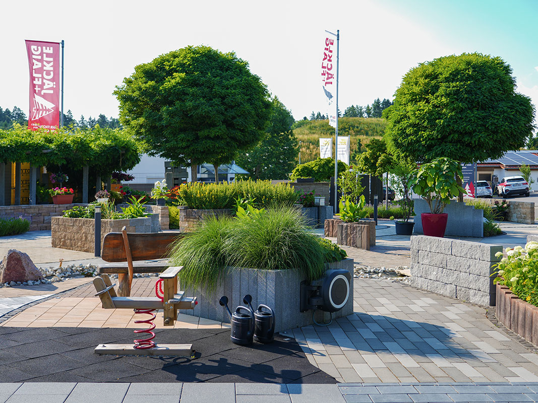 Steingartenausstellung in Niedereschach mit Steinmauern, erhöhten Pflanzenbeeten, Gießkannen, Kinderwippe und Holzbank