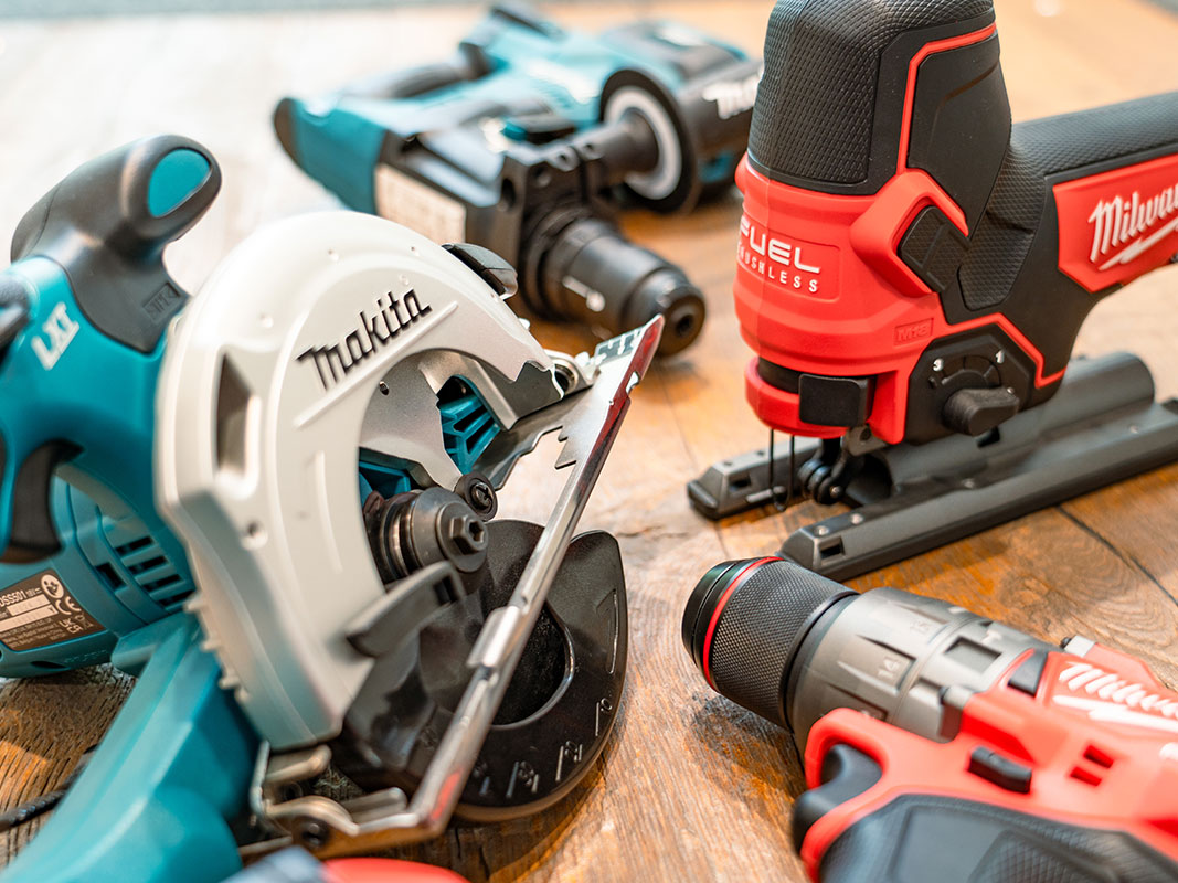 Elektrowerkzeuge wie Sägen, Bohr- und Schlagwerkzeuge auf Präsentationstisch.