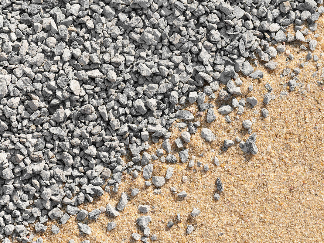 Schüttgüter auf einer Fläche: rechts unten feiner Sand, links oben grober Schutt, in der Mitte treffen beide Materialien aufeinander.